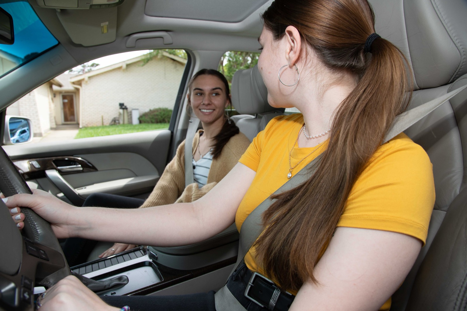A driver and front-seat passenger talking inside a vehicle on a suburban Louisiana street