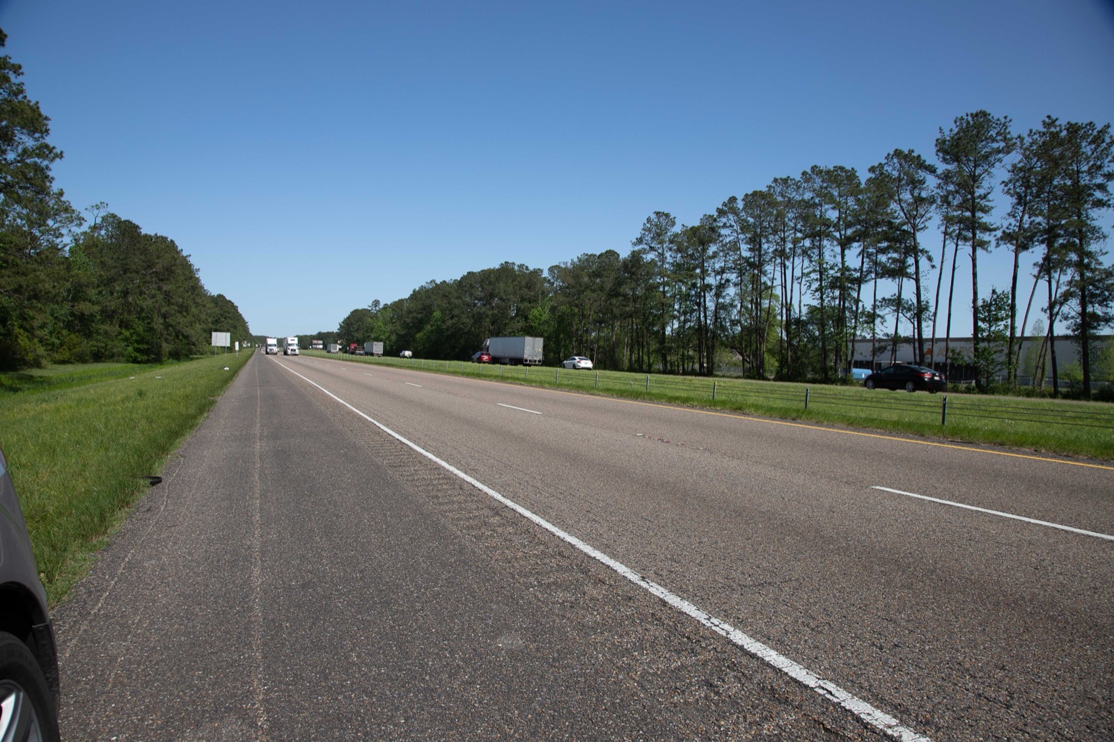 Empty stretch of I-12 eastbound — twin dual carriageway, pine woods, the corridor scheduled for managed-lane conversion