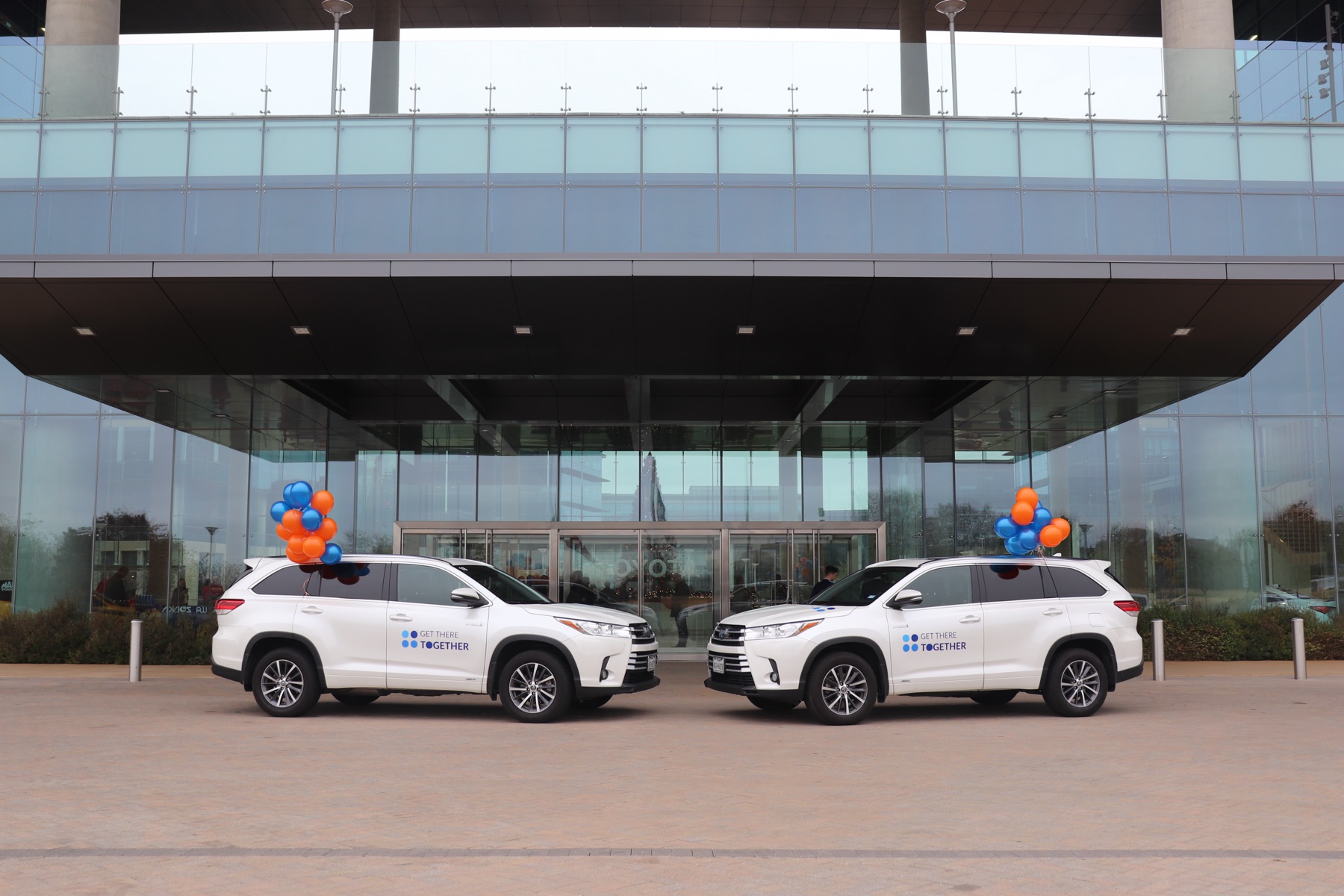 Two GoCarma-branded Toyota Highlanders parked at the entrance of Toyota's Plano headquarters on launch day