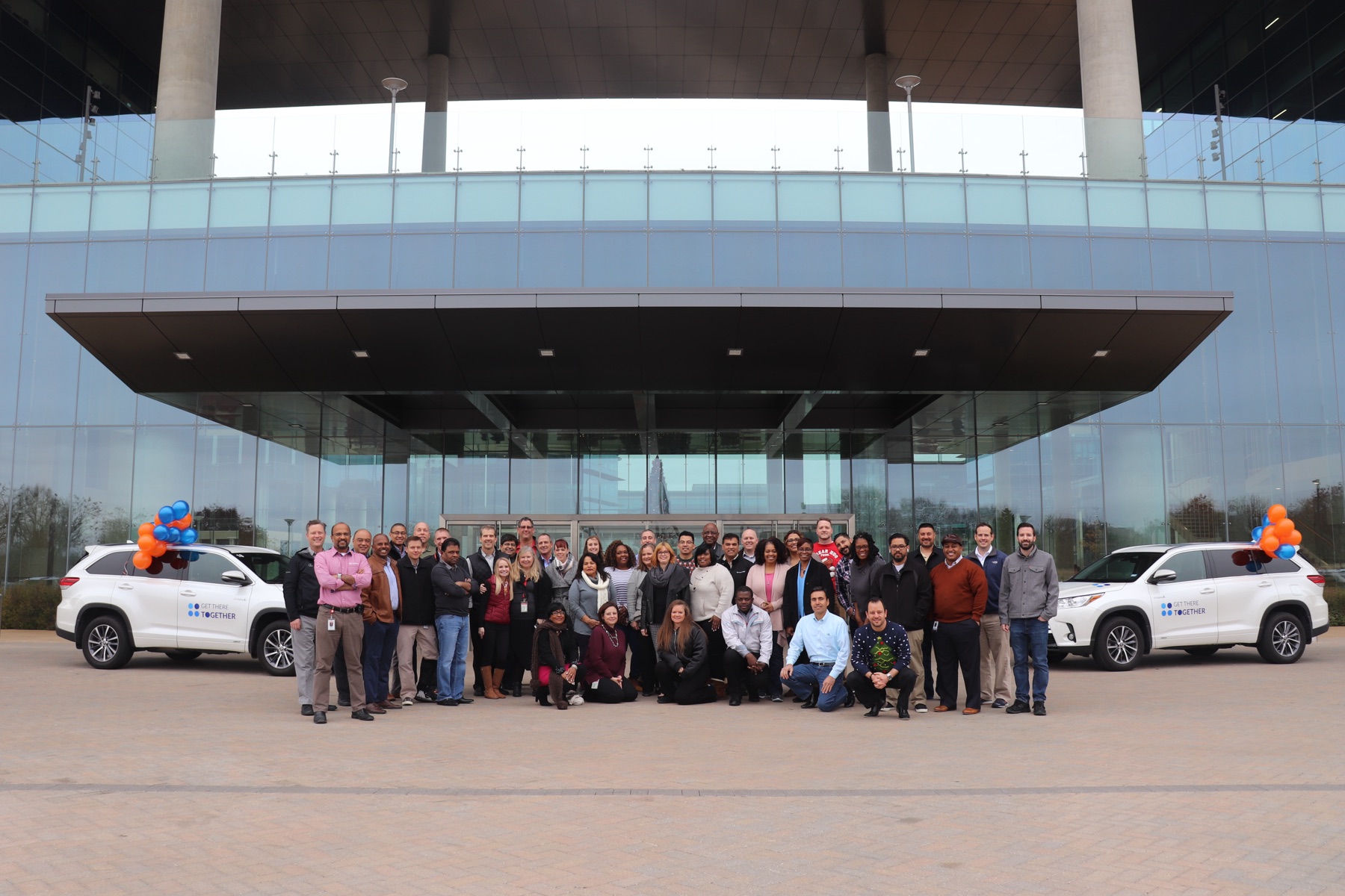 Toyota team gathered at the Plano headquarters entrance with two GoCarma-branded Highlanders on launch day