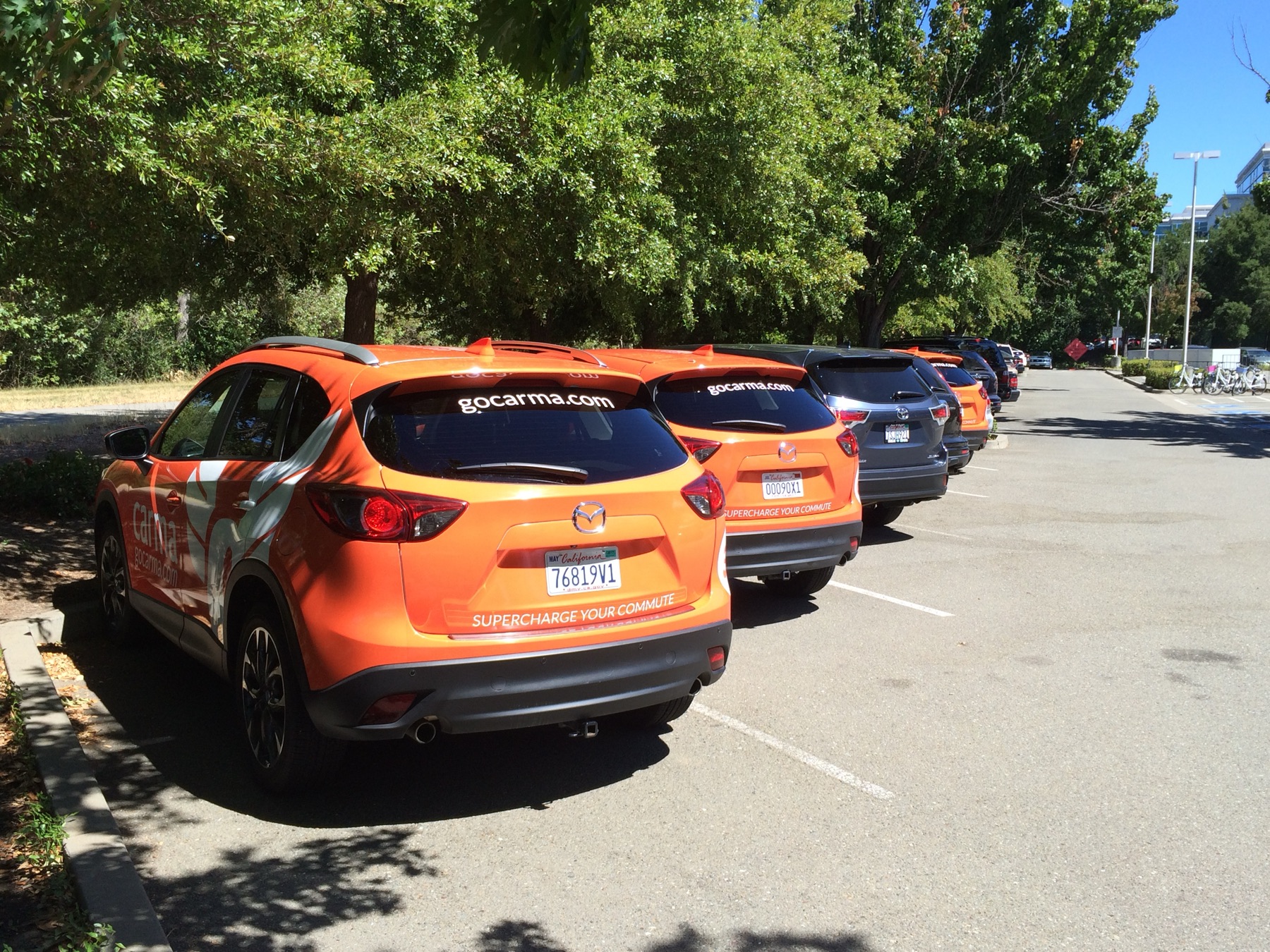 A row of orange Carma Mazda CX-5s with 'gocarma.com · Supercharge your commute' branding